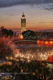 Image du Maroc Professionnelle de  Au coucher du soleil et même un peu avant la foule envahi la fameuse Place Jemaa El Fana qui se métamorphose en un gigantesque restaurant en plein air grâce aux nombreux stands et gargotes qui s'y installent sur ce lieu mythique au centre de la médina de Marrakech. Au fond le minaret de la Koutoubia, Samedi 26 Février 2005. (Photo / Abdeljalil Bounhar)

